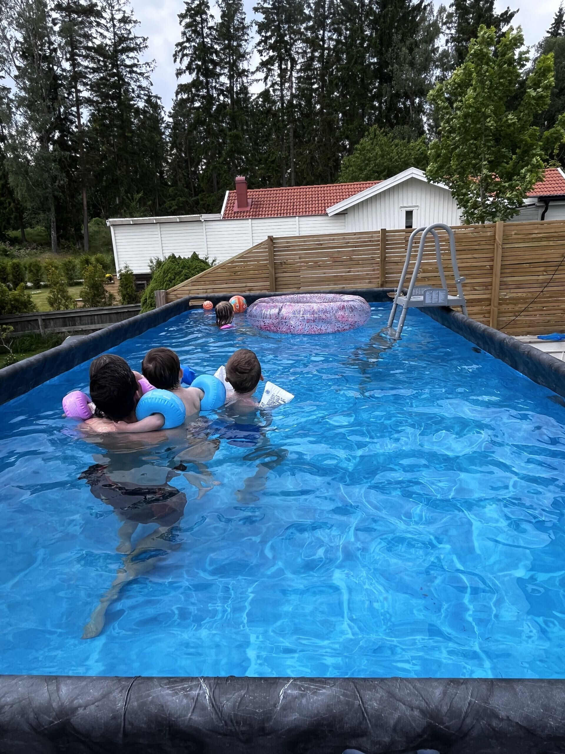 A swimming pool with a wooden deck and a ladder.