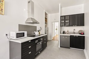 Eine moderne Küche mit Mikrowelle, Backofen und Geschirrspüler, mit schwarzen Schränken und einer weißen Arbeitsplatte.