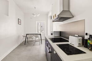 A modern kitchen with a central island, a microwave, a toaster, and a stove. - 90 m² of charm and comfort in the heart of Nantes (Nantes)