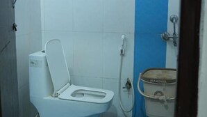 Une petite salle de bain avec des toilettes blanches, un mur bleu et un seau en métal.