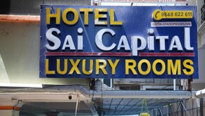 Une enseigne indiquant « HÔTEL Sai Capital, CHAMBRES DE LUXE », avec les numéros de téléphone et un numéro d’identification fiscale (GSTIN).