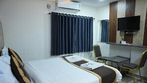 Une chambre d’hôtel équipée d’un lit, d’un bureau, d’une chaise, d’une télévision et d’un appareil de climatisation.