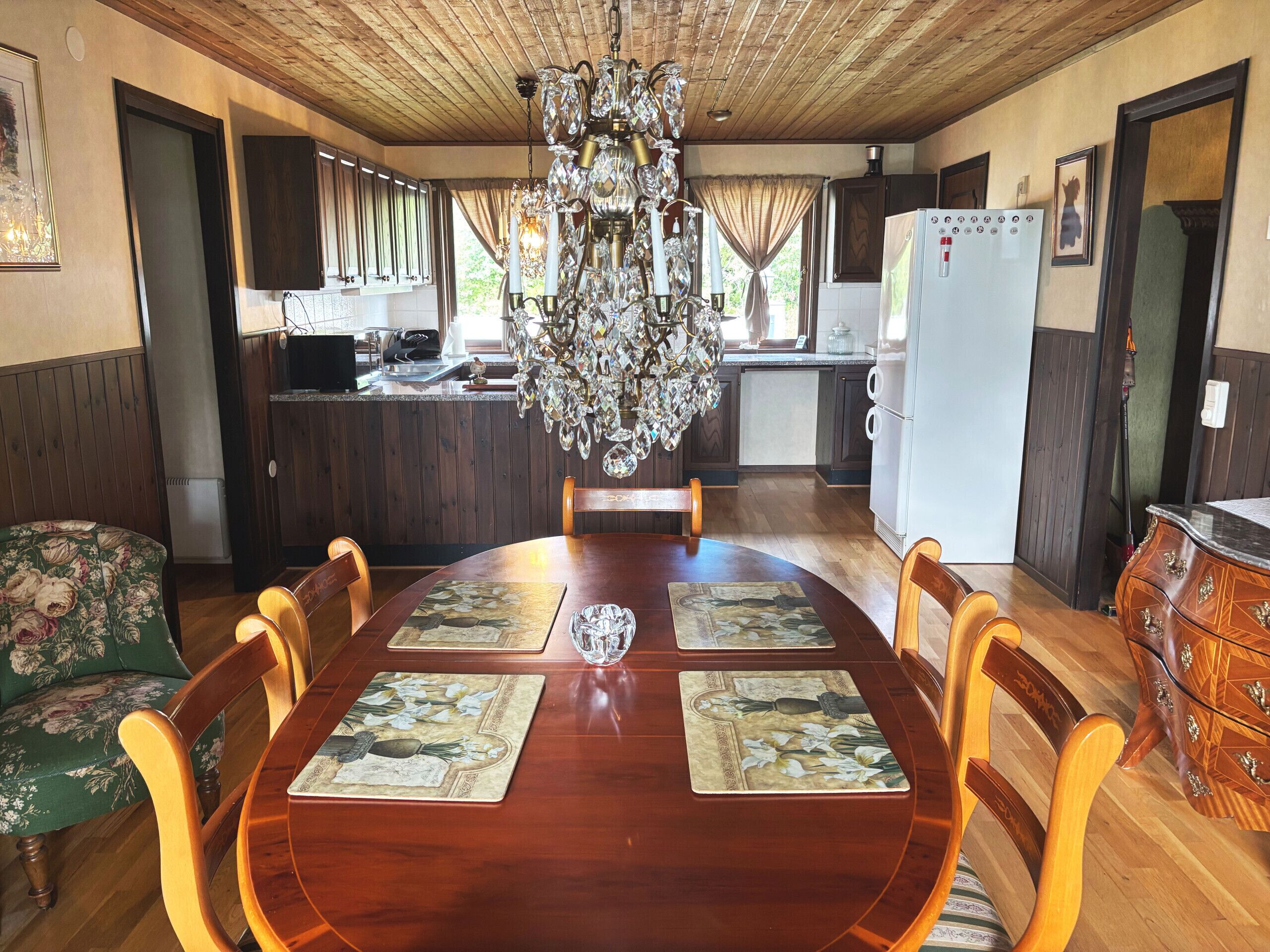 Un comedor con mesa de madera, sillas y una araña.