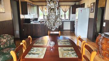 Un comedor con mesa de madera, sillas y una araña.