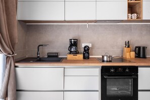 Eine moderne Küche mit Einbauofen, Kaffeemaschine und Wasserkocher auf der Arbeitsfläche.