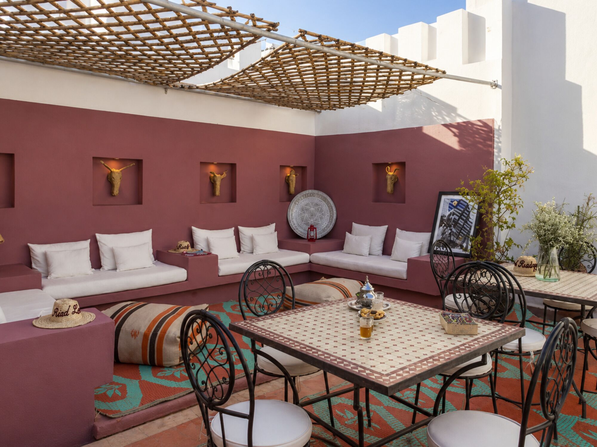 An outdoor seating area with a sofa, chairs, and a table, featuring a patterned floor and decorative wall elements.