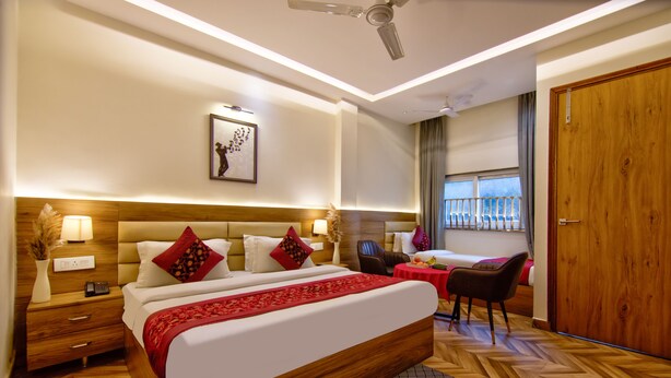 Quarto de hotel com uma cama grande, uma escrivaninha, uma cadeira, uma janela com vista e uma porta.