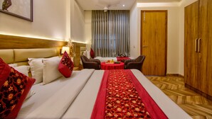 Quarto de hotel com cama, escrivaninha, cadeira, guarda-roupa e janela com cortinas.