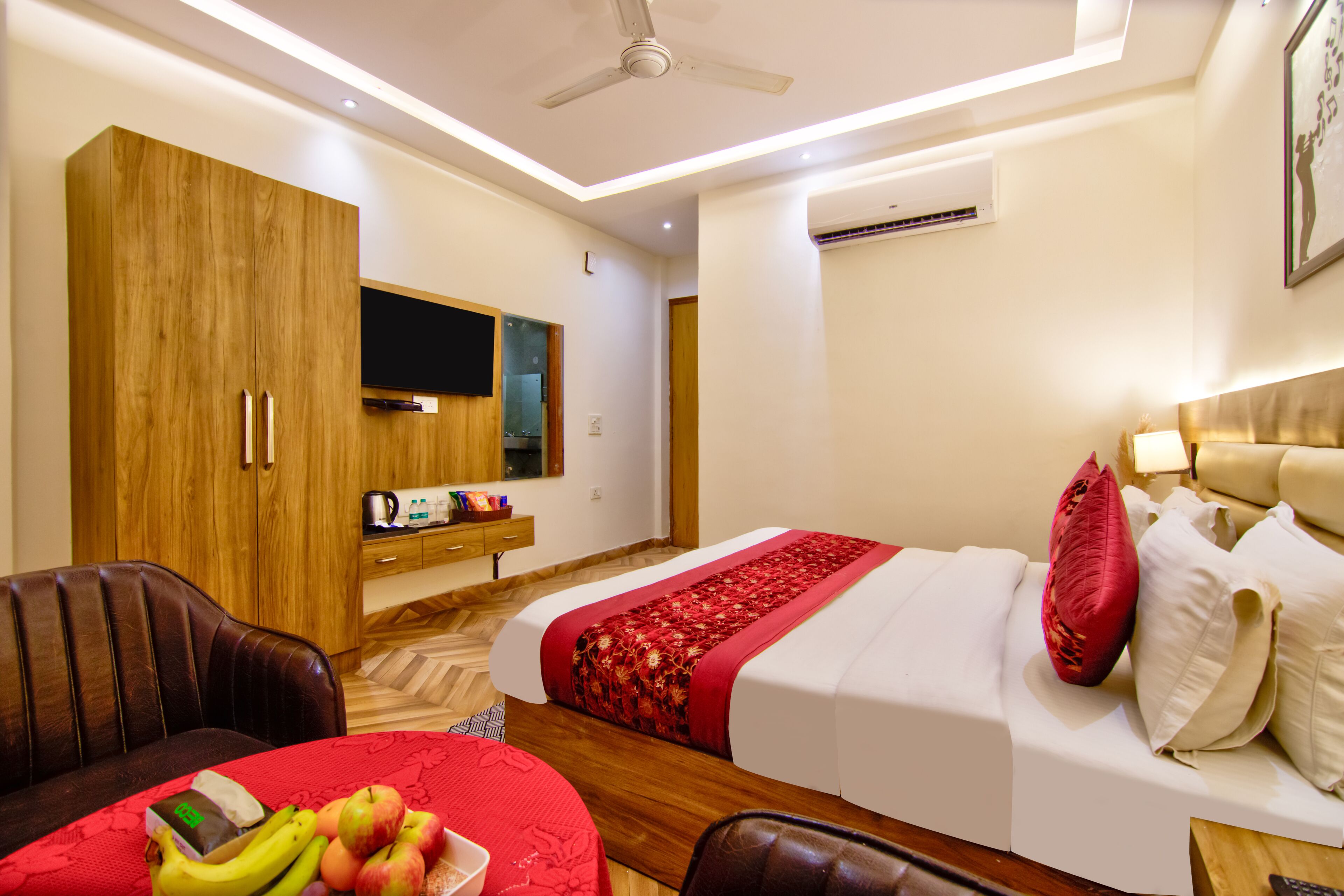 A hotel room with a bed, a sofa, a TV, and a kitchenette.