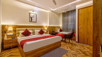 Quarto de hotel com uma cama grande, mesas de cabeceira, escrivaninha, cadeira, guarda-roupa e ventoinha no teto.