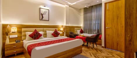 A hotel room with a large bed, bedside tables, a desk, a chair, a wardrobe, and a ceiling fan.
