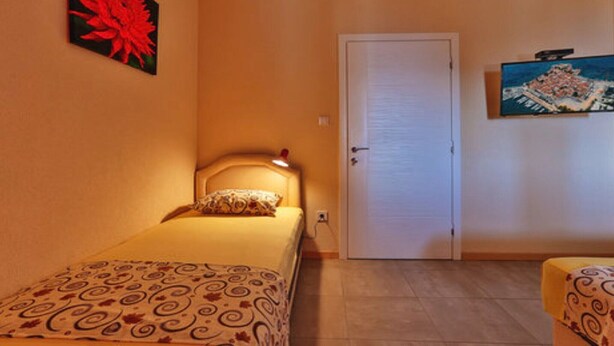 Ein Schlafzimmer mit einem Bett, einer Tür und zwei Bildern an den Wänden.