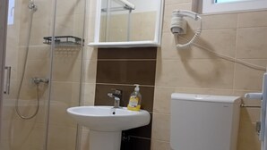 Ein Badezimmer mit einer Duschkabine, einem weißen Waschbecken und einer Toilette.