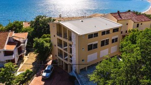 Un edificio de varios pisos con techo plano, situado cerca de la costa y con vista despejada al mar.