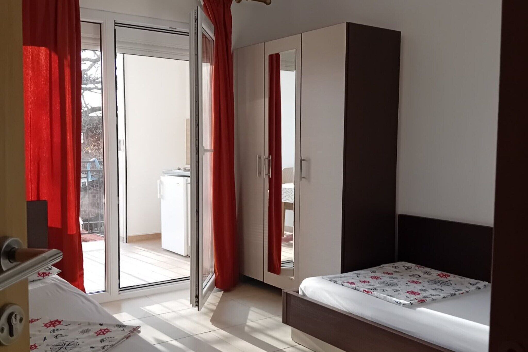 Une chambre à coucher comprenant un lit, une armoire et une porte-fenêtre coulissante donnant sur un balcon.