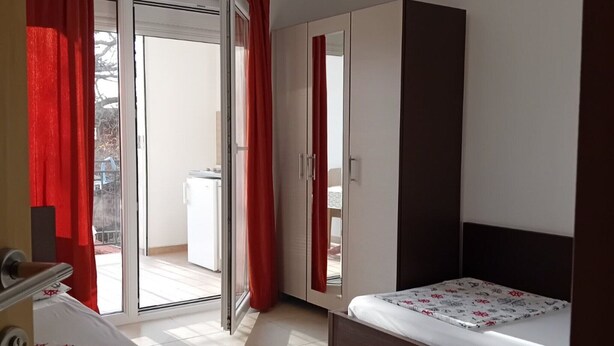 Un dormitorio con cama, armario y puerta corrediza de vidrio que da a un balcón.