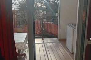 Ein Balkon mit Tisch, Stühlen, einem Metallgitter und einem Kühlschrank.