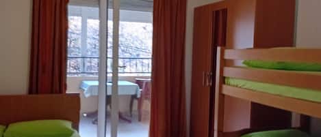 A room with a bunk bed, a wardrobe, and a sliding glass door leading to an outdoor area.