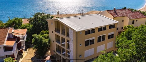 A multi-story building with a flat roof, adjacent to a coastline with a clear view of the sea.