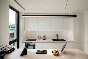 Uma cozinha moderna com armários brancos, bancada preta e janela com vista para a cidade.