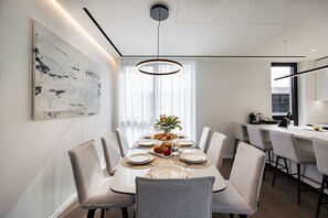 Un espace de salle à manger moderne, avec une longue table dressée pour six personnes, entourée de chaises.