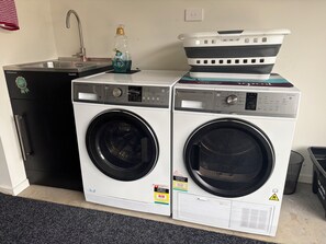 A laundry area with two front-loading washing machines, a sink, and a detergent bottle.