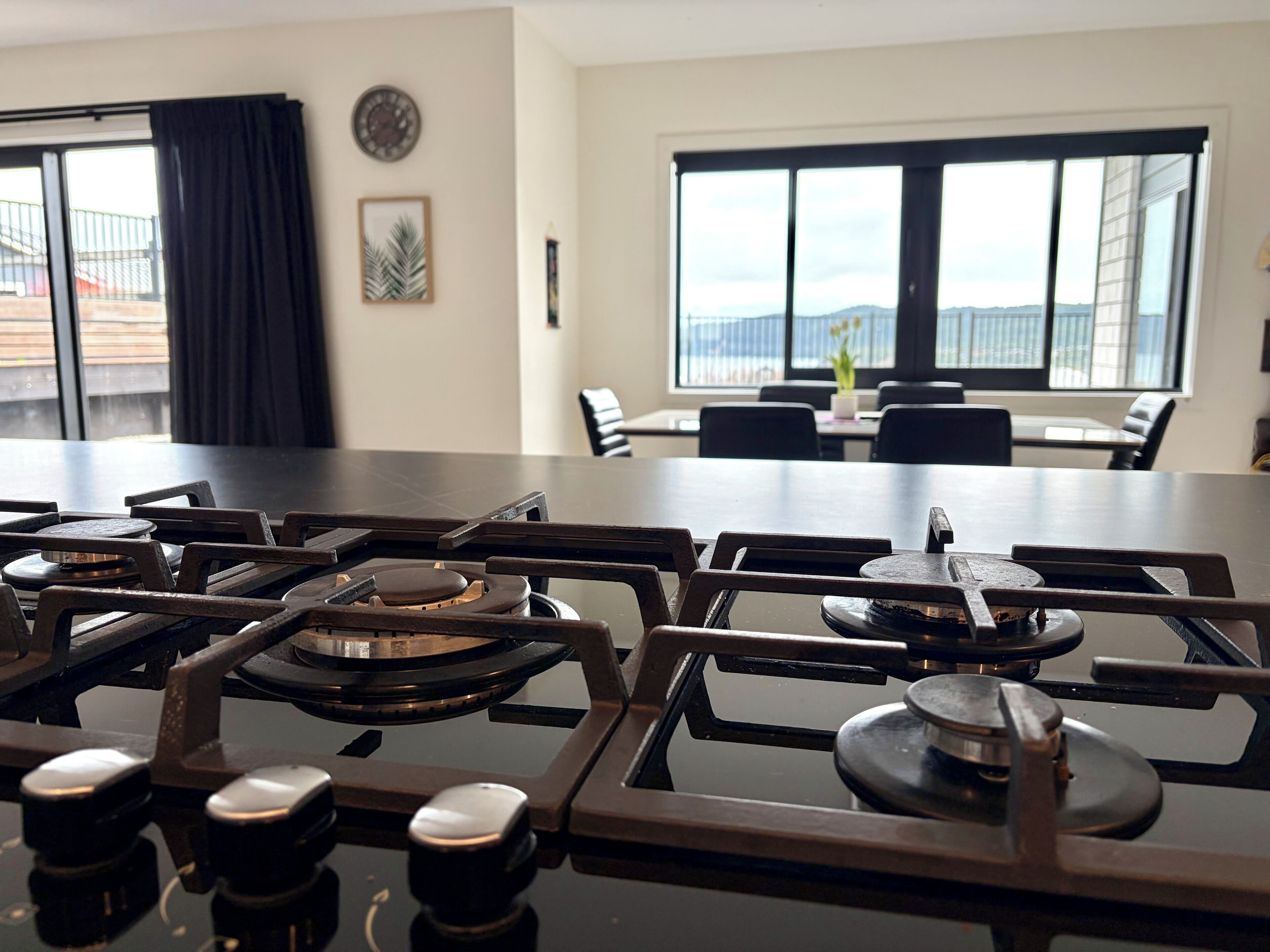 A kitchen with a gas stove, dining table, chairs, and large windows with a view.
