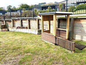 A wooden deck with a built-in bench and a small covered seating area.