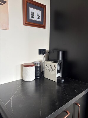 A kitchen counter with a coffee maker, a kettle, and a mug.