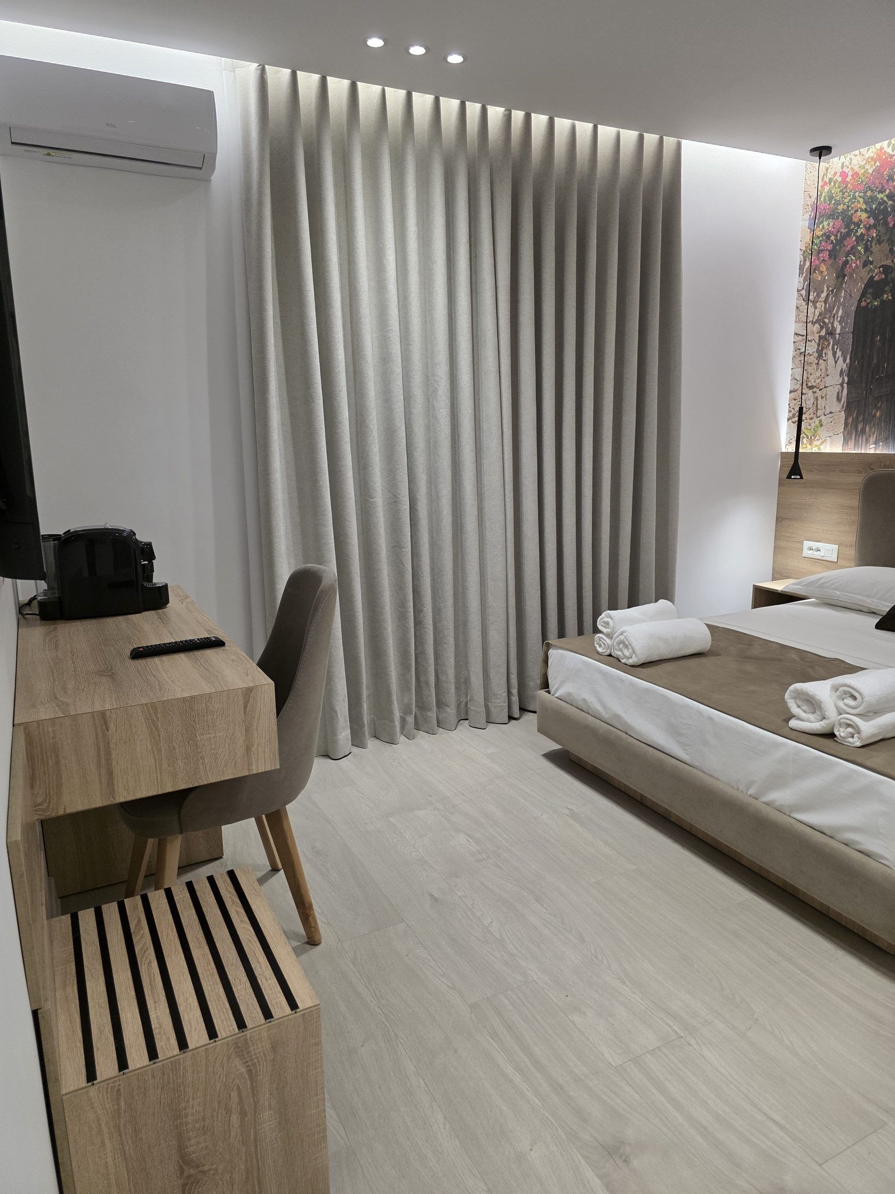 Una habitación de hotel moderna con cama, escritorio, silla, televisión y ventana con cortinas.