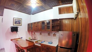 Una cocina con armarios de madera, un refrigerador de acero inoxidable, un fregadero y un microondas.