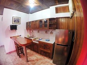 A kitchen with wooden cabinets, a stainless steel refrigerator, a sink, and a microwave.