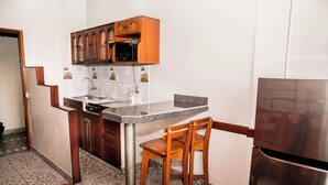 Una cocina compacta con gabinetes de madera, un refrigerador de acero inoxidable, un microondas y un lavabo.