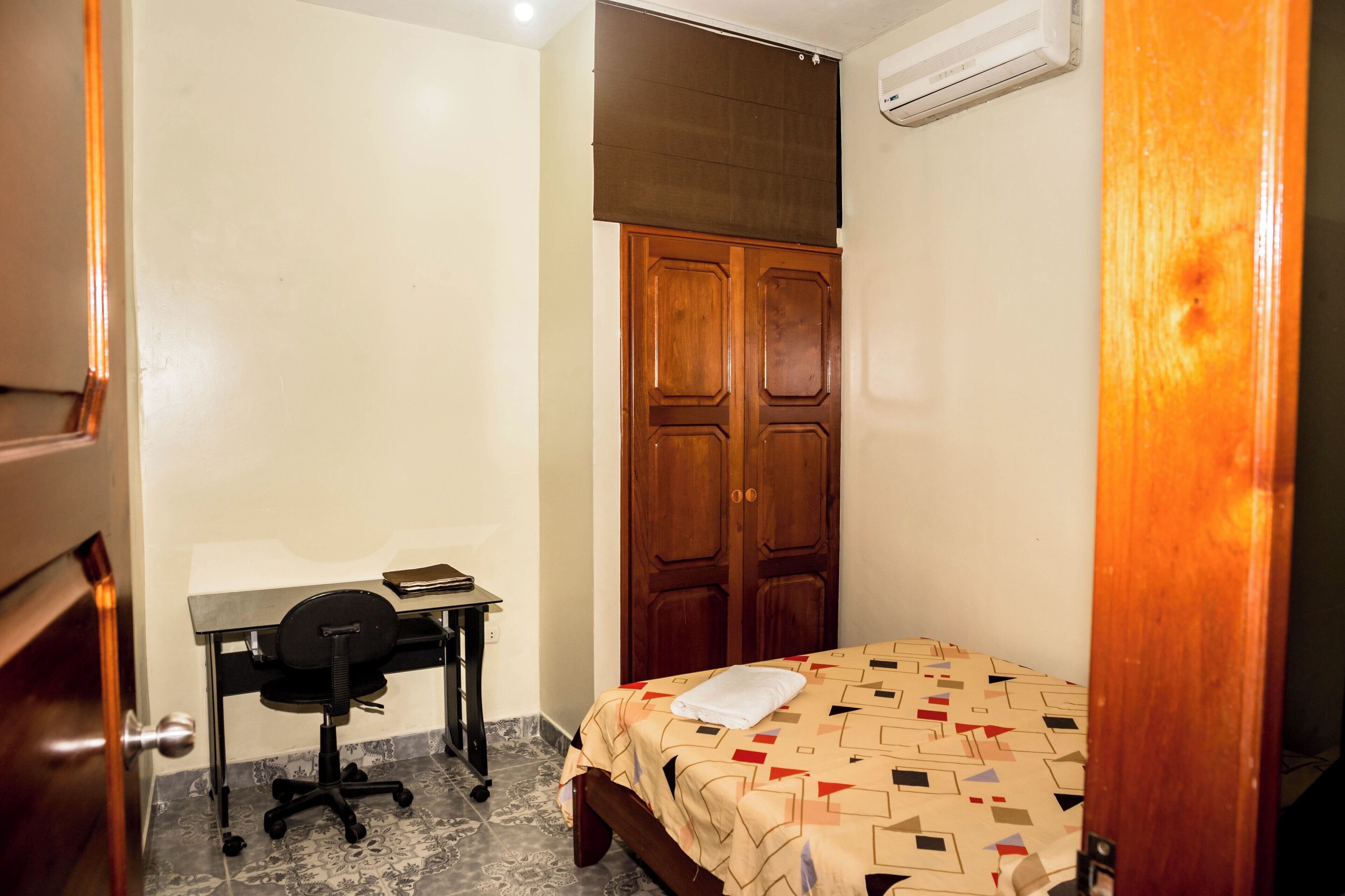 A bedroom with a bed, a desk, a chair, and a wardrobe.