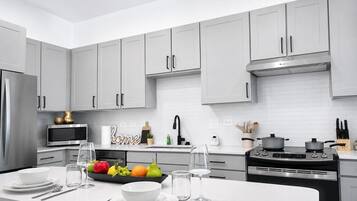 A modern kitchen with grey cabinets, stainless steel appliances, and a central island with dining setup.
