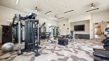 A gym with various exercise equipment, a patterned floor, and a television on the wall.