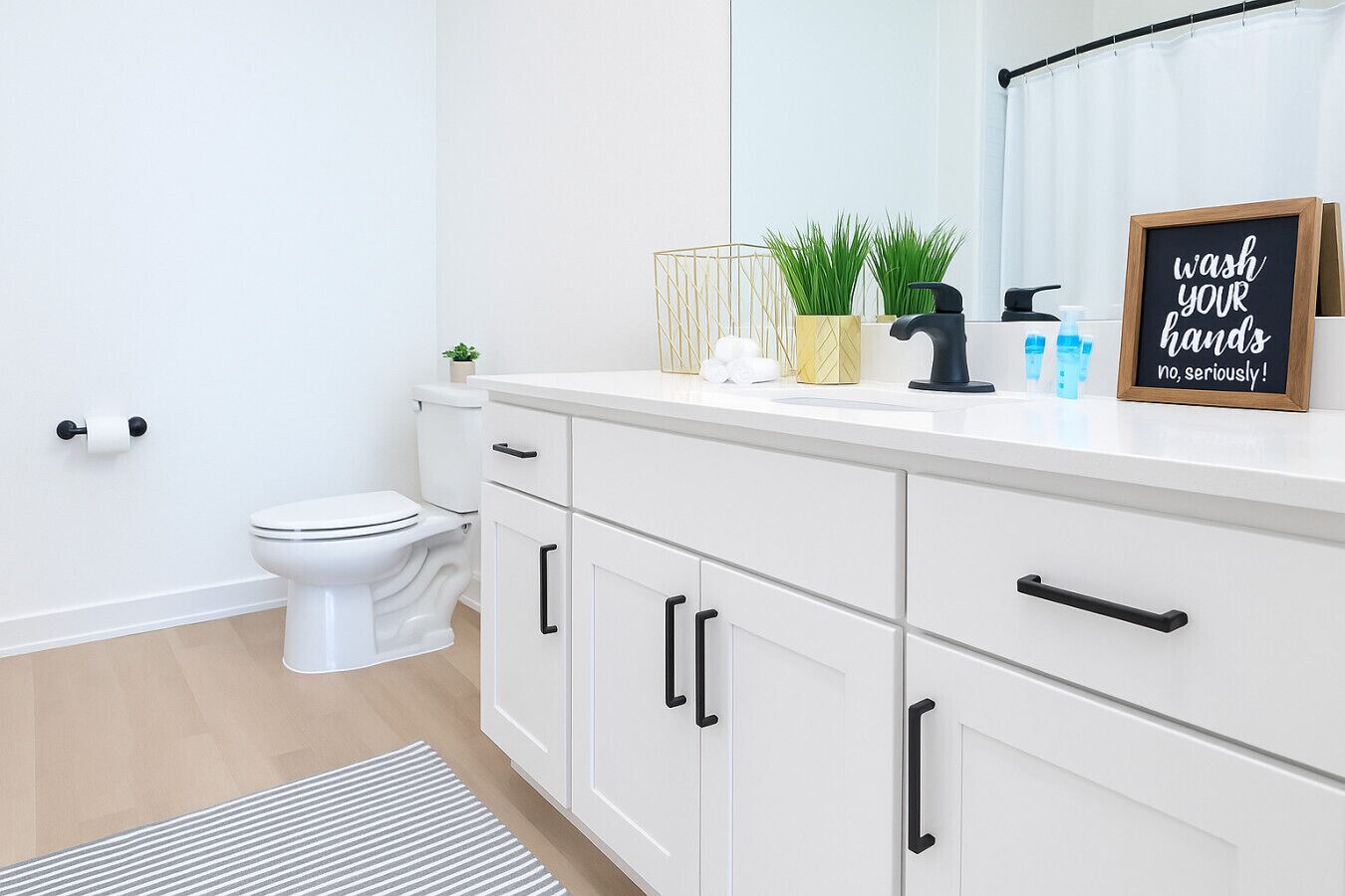 A modern bathroom with a toilet, white cabinets, and a countertop with toiletries.
