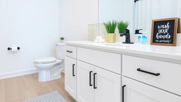 A modern bathroom with a toilet, white cabinets, and a countertop with toiletries.