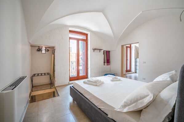 A bedroom with a bed, a radiator, a window, and a door. - Domus Fisculi A: Authentic Apulian Stone-Vaulted Home (Fasano)