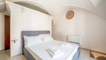 A modern bedroom with a large bed, a bedside table, and a wall-mounted light fixture.