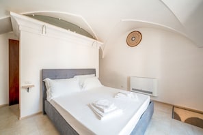 Een moderne slaapkamer met een groot bed, een nachtkastje en een wandlamp.