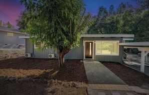 A modern house with a tree in the yard, a covered porch, and a pathway leading to the entrance. - Ultimate Peaceful Country Retreat in Sonora DT (Sonora)