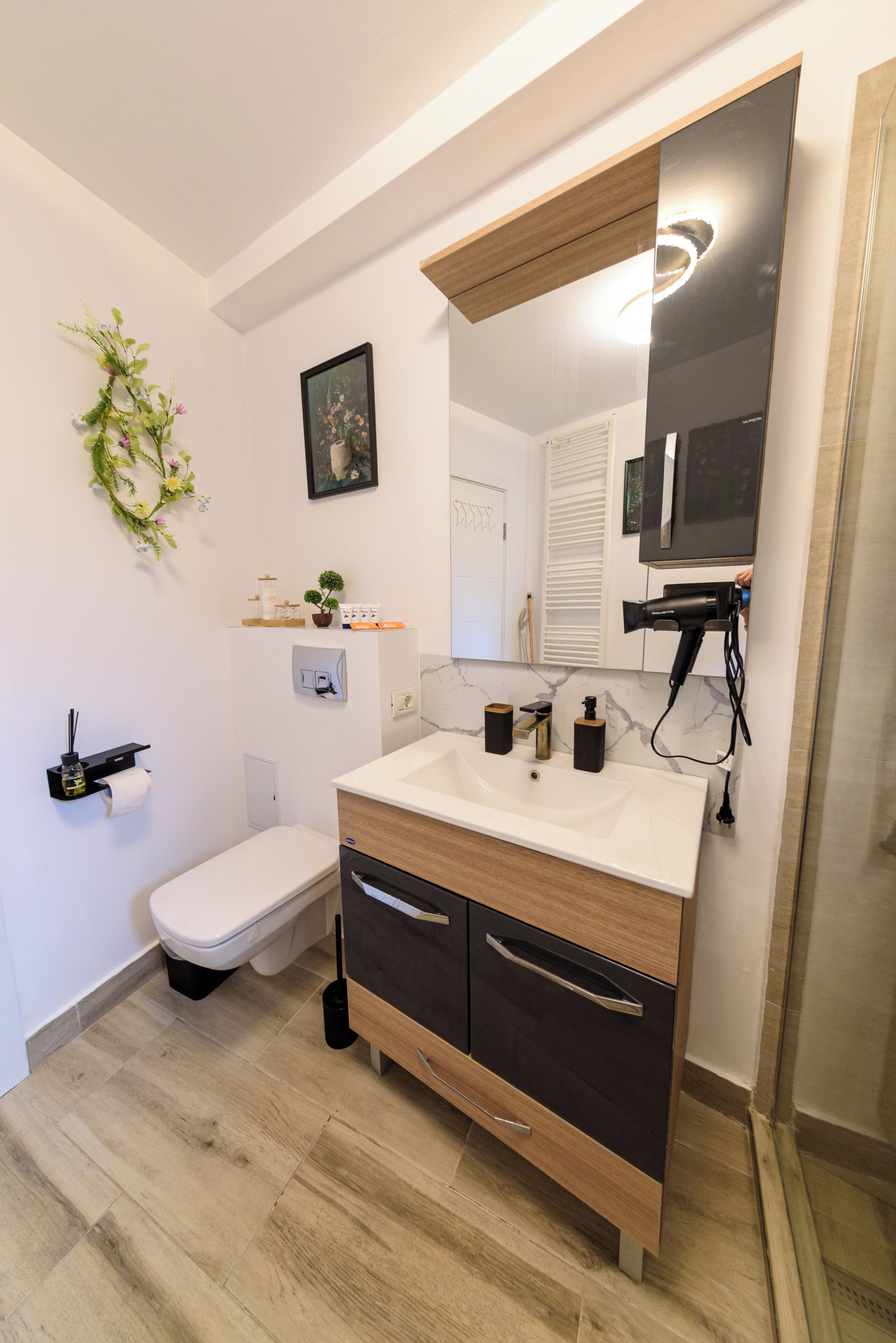 Un baño moderno con inodoro, lavamanos, espejo y ducha.