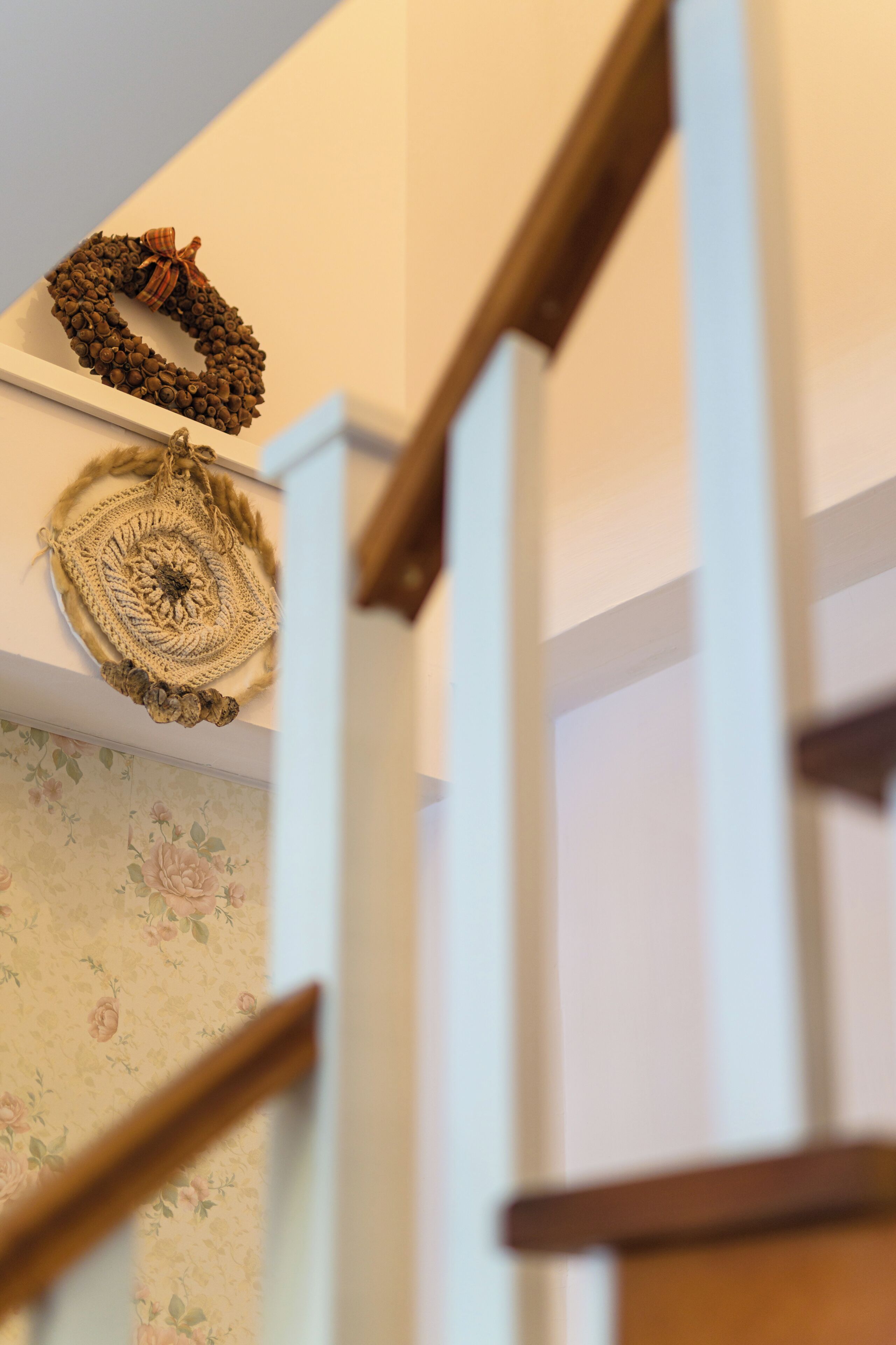 A staircase with a wooden handrail and a wall with floral wallpaper.