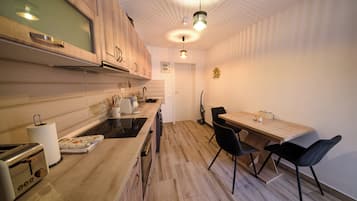 A modern kitchen with wooden cabinets, a built-in oven, and a dining area with a table and chairs.