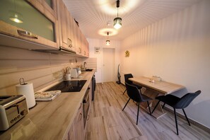 A modern kitchen with wooden cabinets, a built-in oven, and a dining area with a table and chairs.