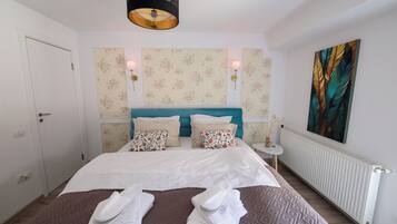 Une chambre d’hôtel avec un lit, deux lampes fixées au mur, un radiateur et un grand tableau.