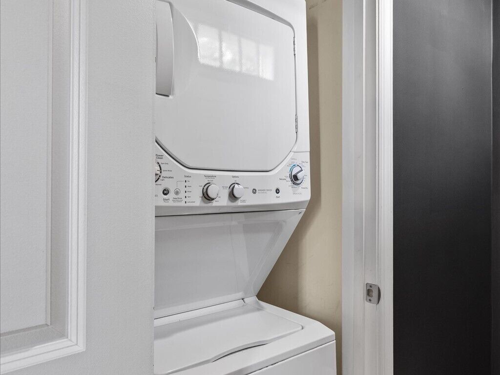 Un appareil combiné lave-linge et sèche-linge blanc, doté de boutons de commande et d’un bouton de démarrage.
