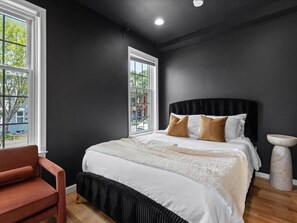 A bedroom with a large bed, a window, a chair, and a stone table. - 2 Mins from King St < > A Boutique Old Town Xcape (Alexandria)