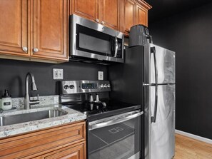 A kitchen with stainless steel appliances, wooden cabinets, and a granite countertop. - 2 Mins from King St < > A Boutique Old Town Xcape (Alexandria)